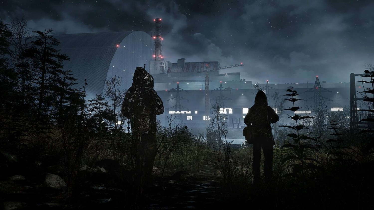 Two hooded figures stand in overgrown foliage facing a brightly lit industrial facility under a cloudy night sky