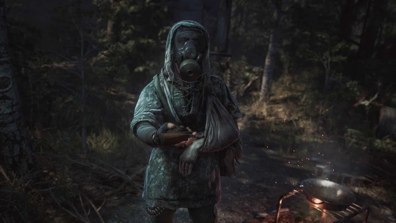 Person wearing camouflage jacket and gas mask extending an object towards the viewer near a campfire in a dark forest