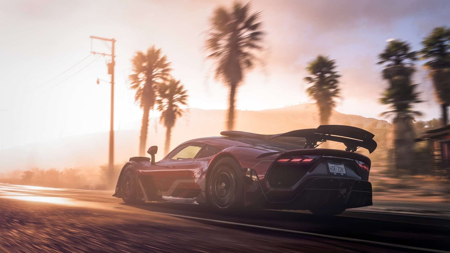 Red sports car driving fast on a sunlit road with palm trees and hills in the background at sunset