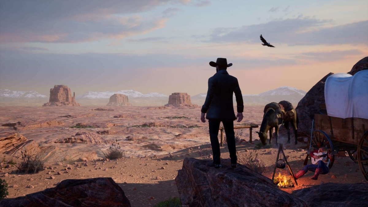A cowboy in a black hat stands on rocks overlooking a vast desert landscape with mesas, while a man plays guitar by a campfire next to a covered wagon and two horses.