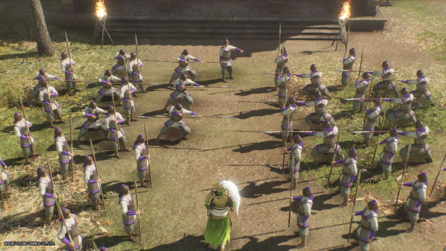 Armoured warrior in green confronts multiple spearmen soldiers arranged in a battle formation outdoors