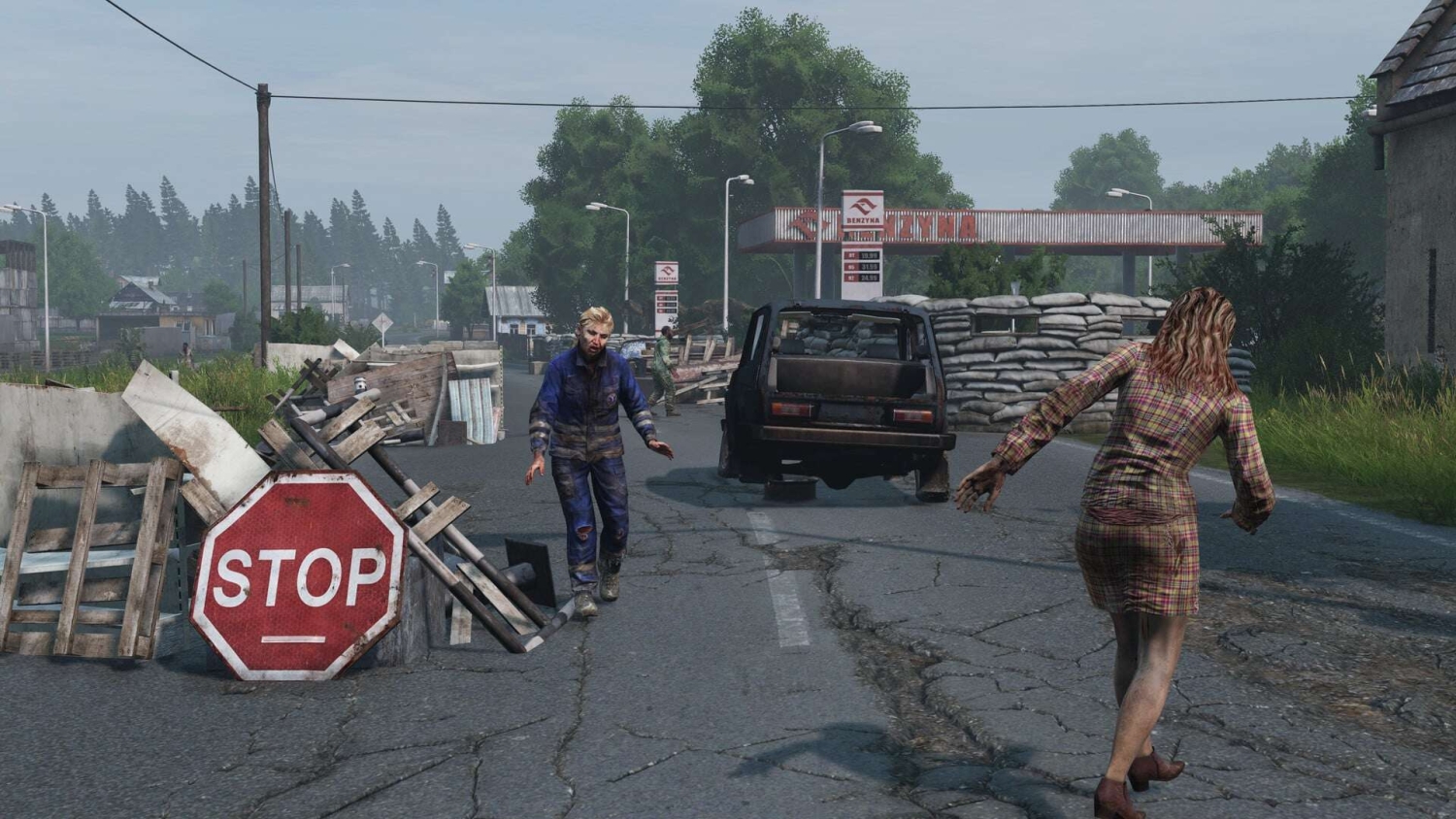 Two zombies wandering near a makeshift barricade and damaged vehicle on cracked street
