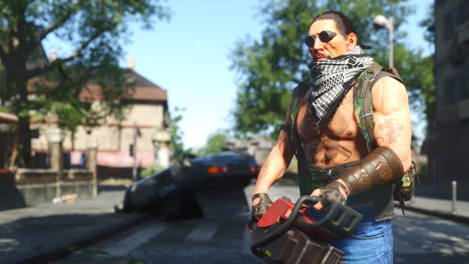 Muscular man wearing sunglasses and patterned scarf holding a red chainsaw on a street with an overturned car in background