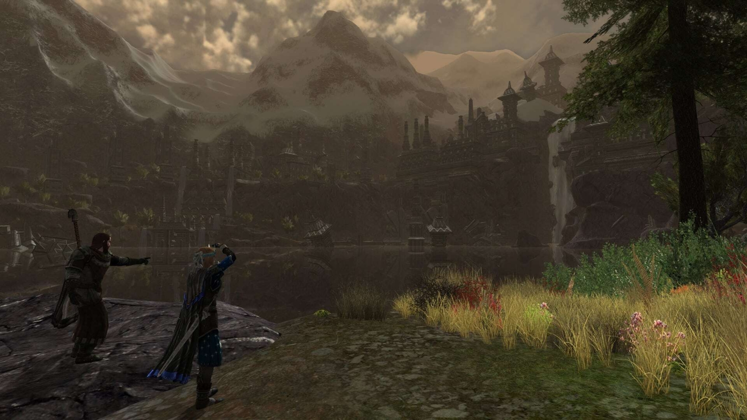 Two characters stand on a rocky shore beside a lake looking towards a dark fortress with mountains in the background