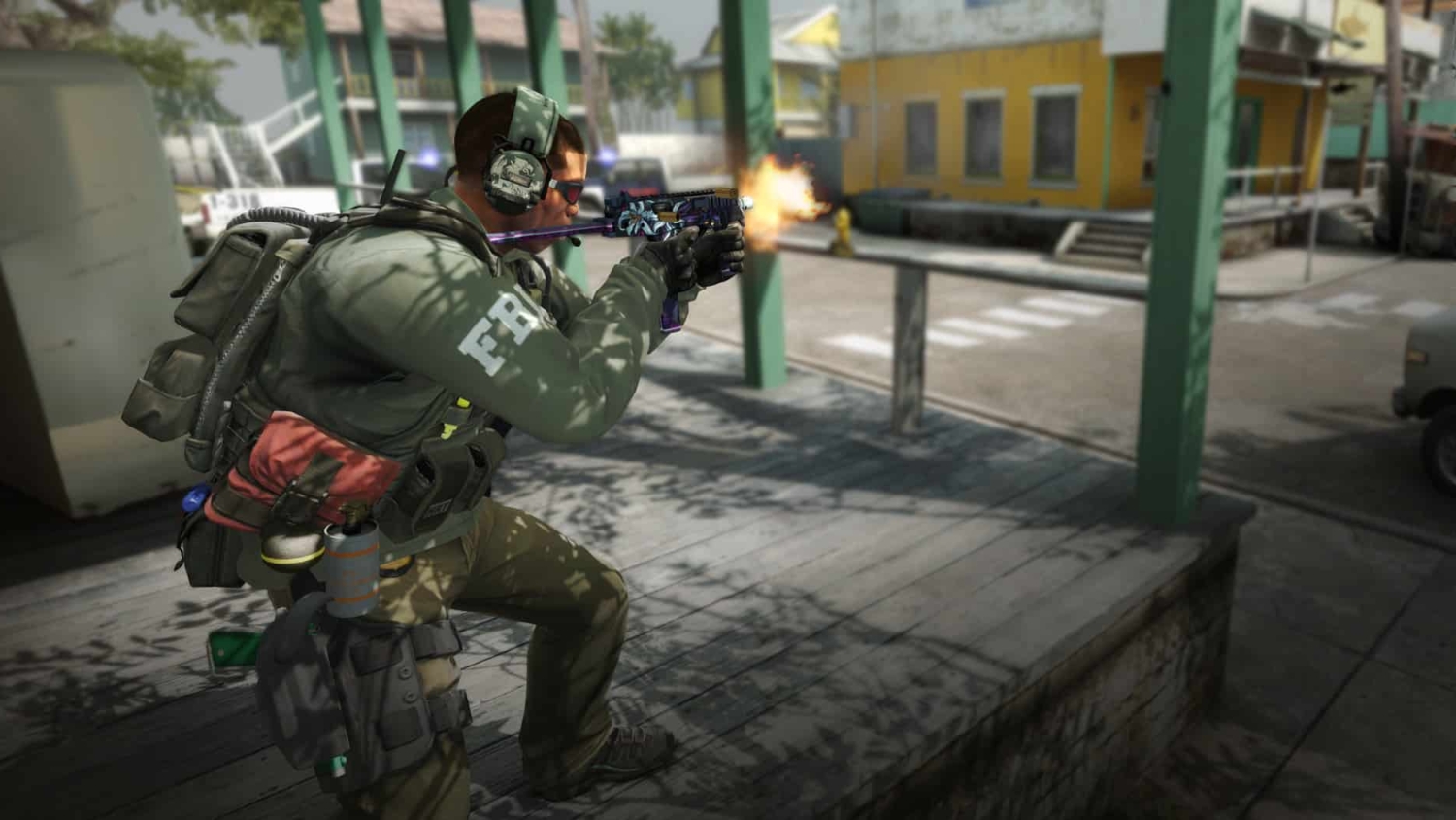 Soldier wearing tactical gear and headphones firing a pistol on an urban street under sunlight