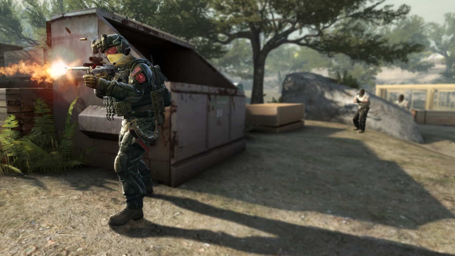 Armoured soldier firing rifle outdoors beside metal container with two armed opponents in background