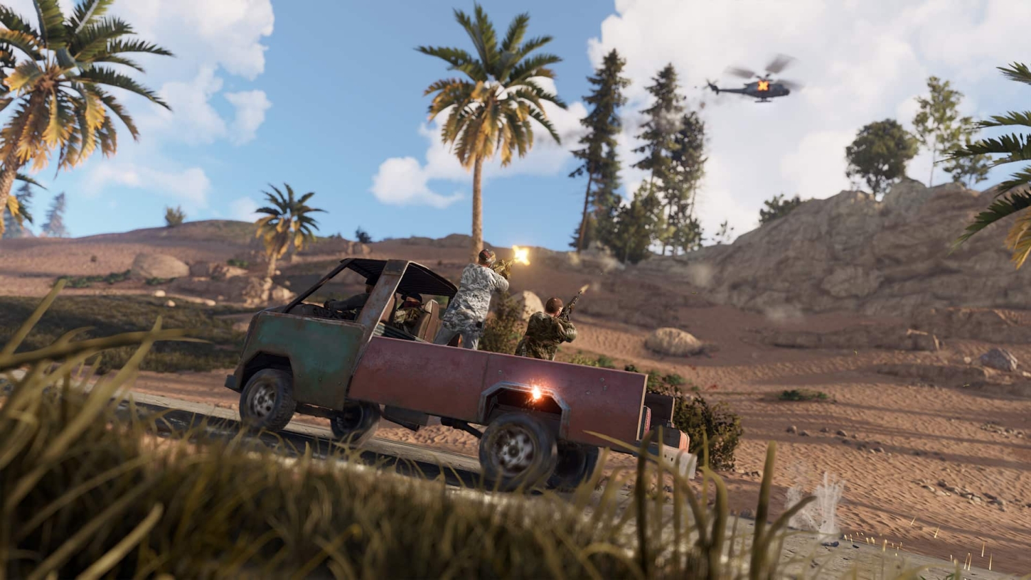 Two men firing guns from the back of an old pickup truck in a desert with palm trees and a helicopter overhead