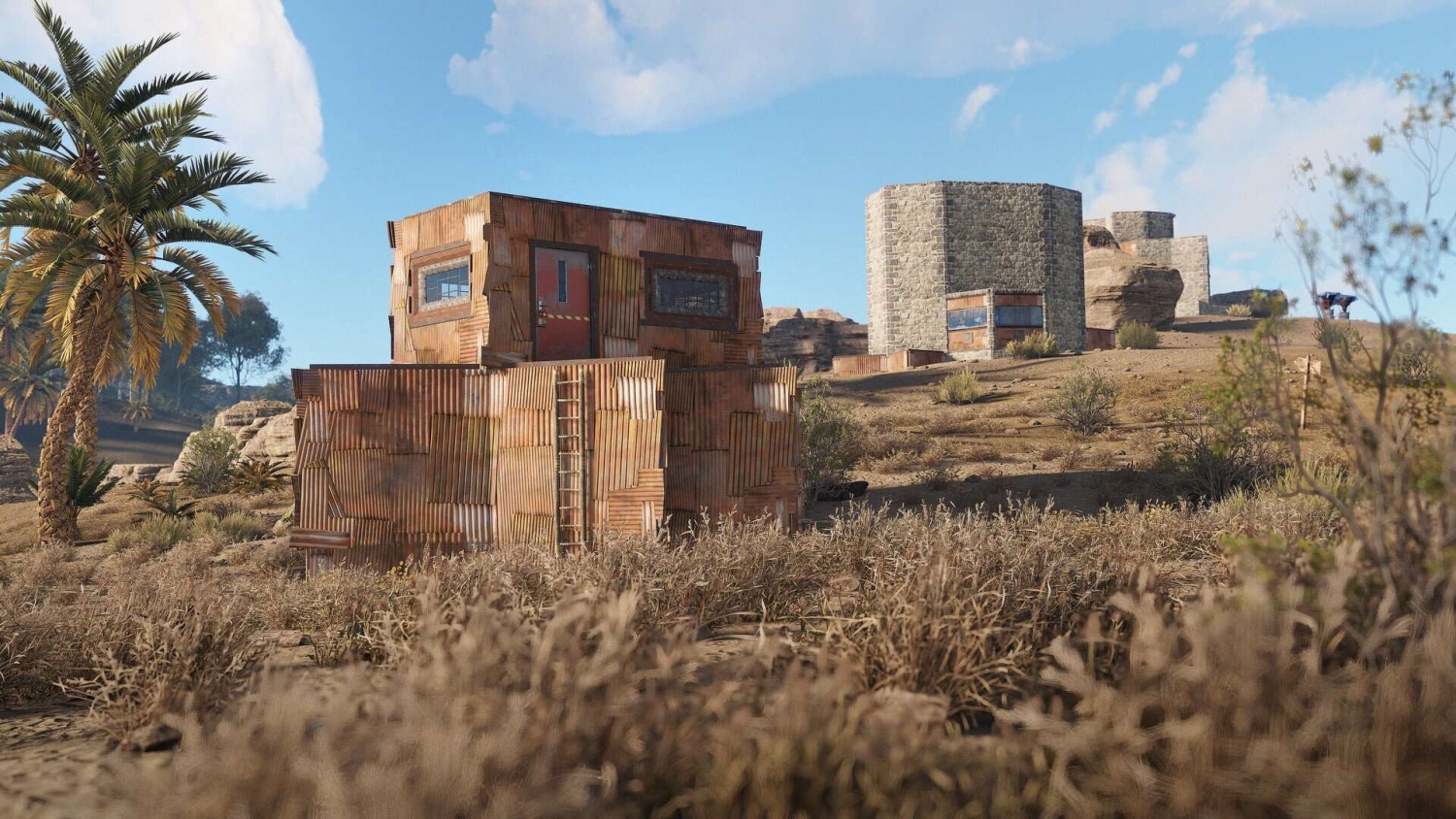 Player-built wooden and stone structures in dry, grassy landscape under clear blue sky