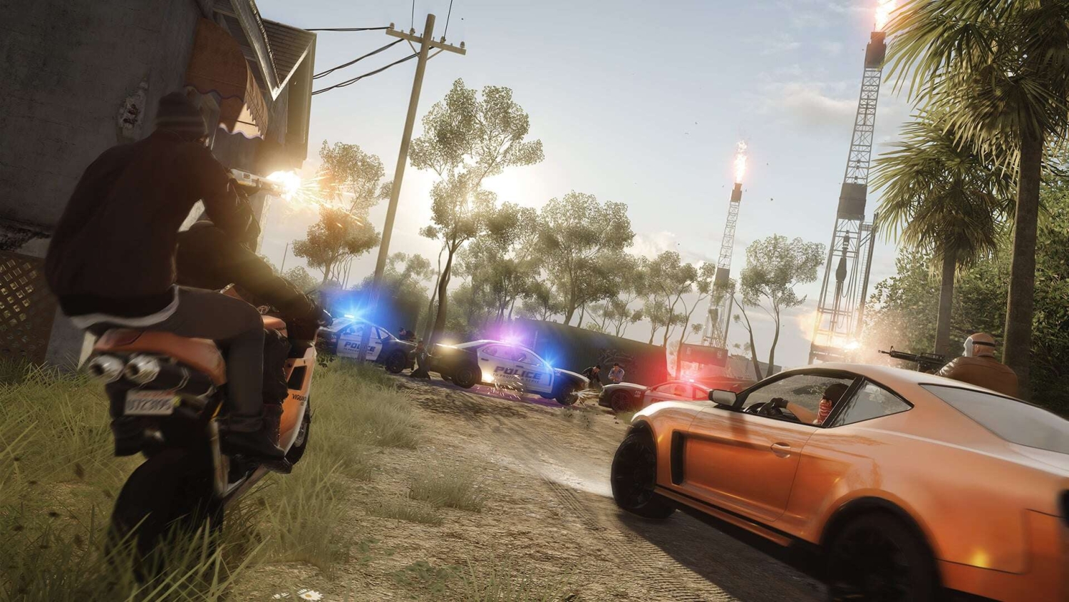 Two men on a motorcycle firing a gun at police cars with flashing lights near oil rigs on a dirt road