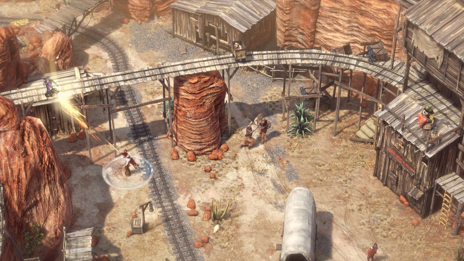 Top-down tactical view of characters fighting near wooden railway tracks and old mining buildings in a desert setting