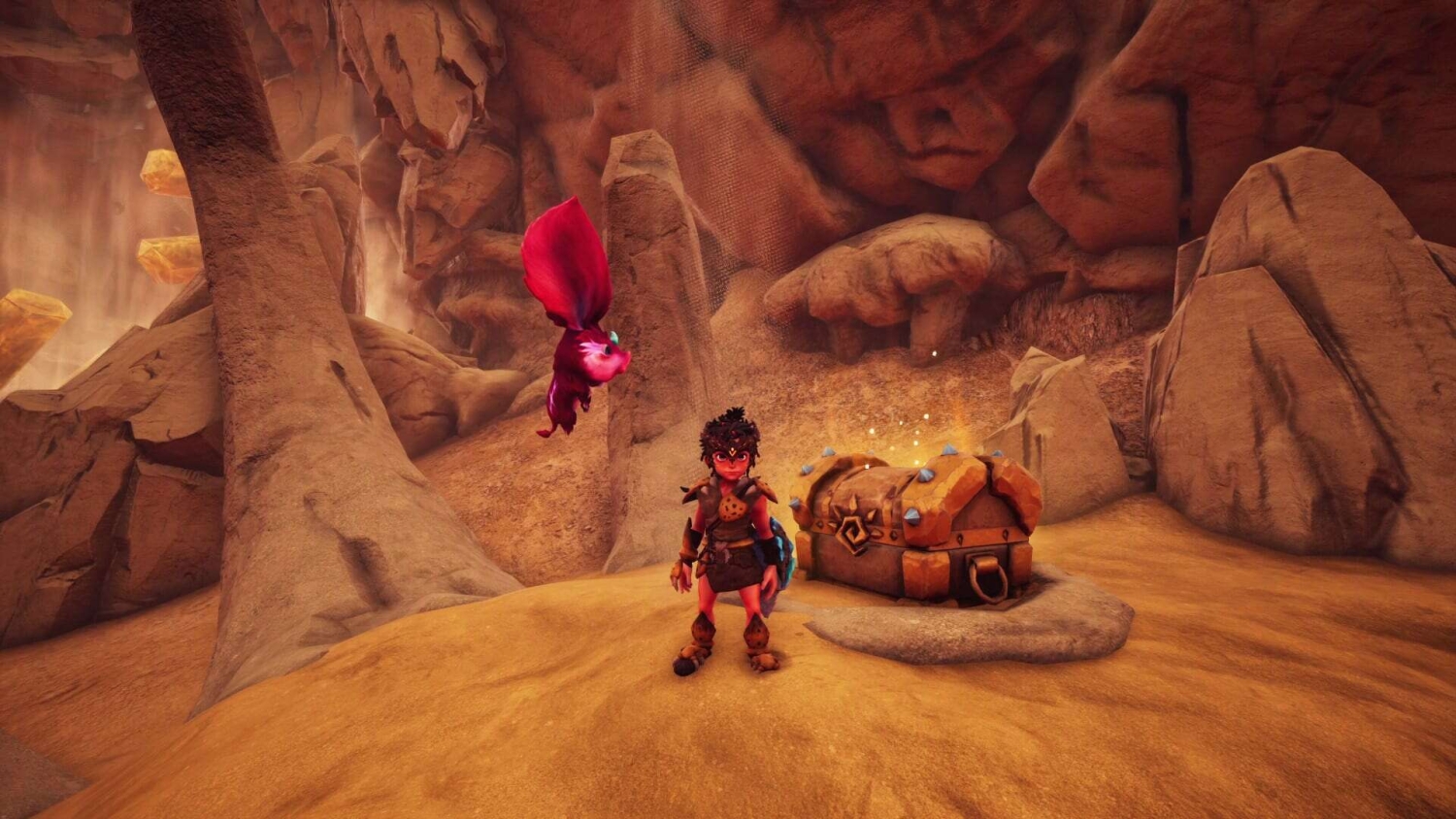 Young tribal character stands in rocky cave near a glowing treasure chest with a pink floating creature