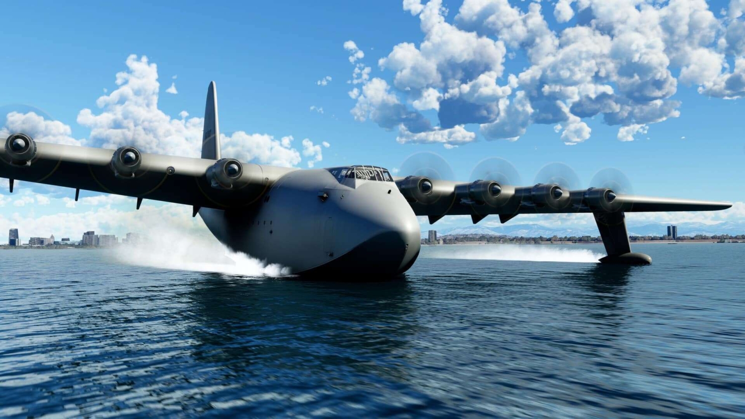 Grey seaplane with eight spinning propellers skimming across water towards a distant city coastline under blue sky