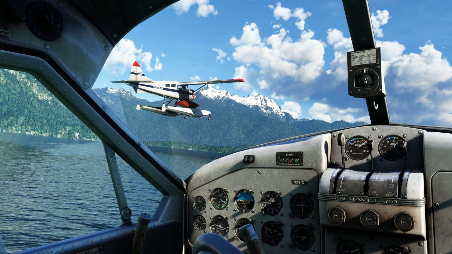 View from seaplane cockpit showing another seaplane flying over a lake with forested mountains and blue sky