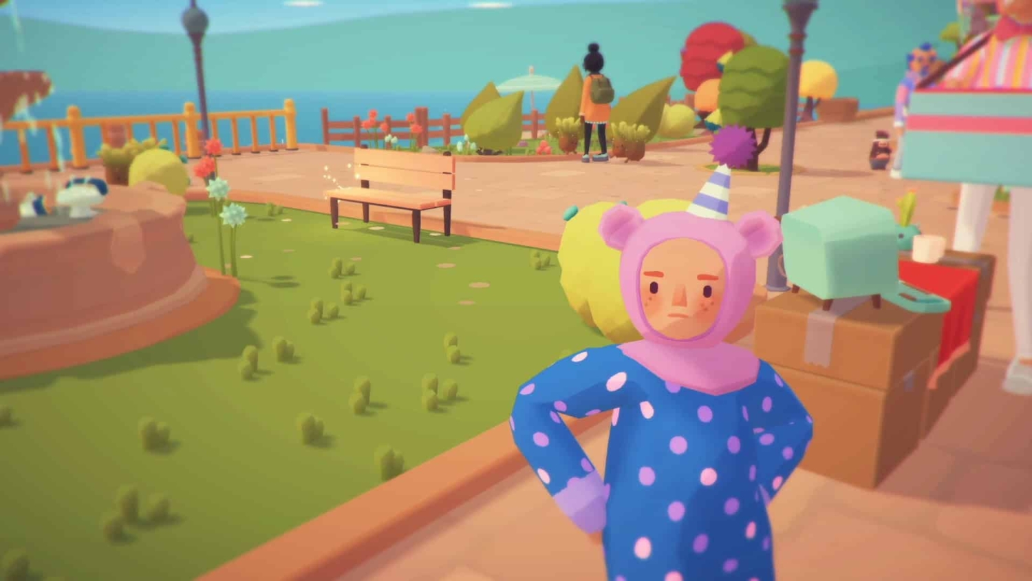 Person wearing a purple bear costume with a party hat standing in a colourful garden area with benches and plants