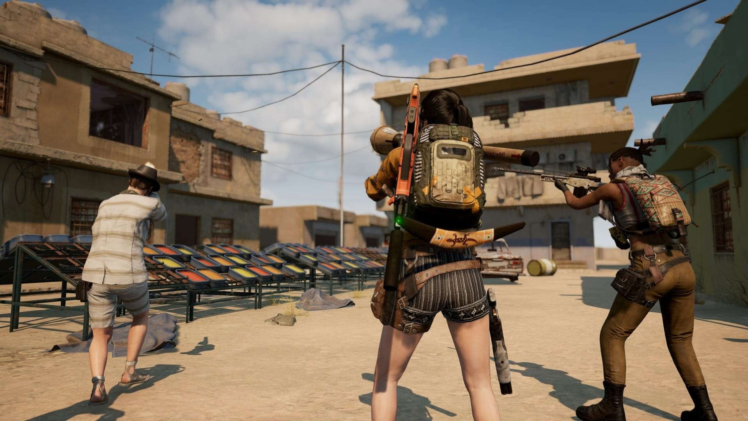 Three armed characters aiming weapons forward in a deserted town with damaged buildings during gameplay