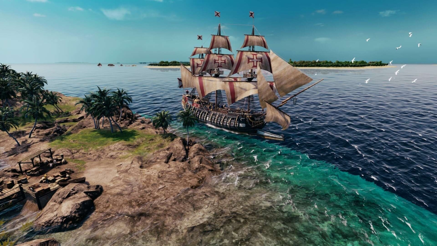 Large historic sailing ship with red cross sails navigating close to a tropical island coastline under a clear blue sky
