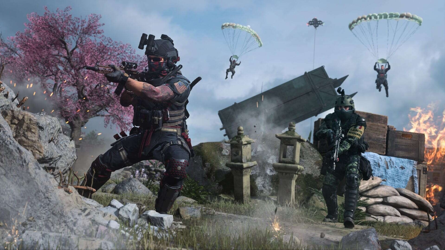 Two soldiers in tactical gear take cover behind rocks and crates during an intense battle with parachuting players in the sky