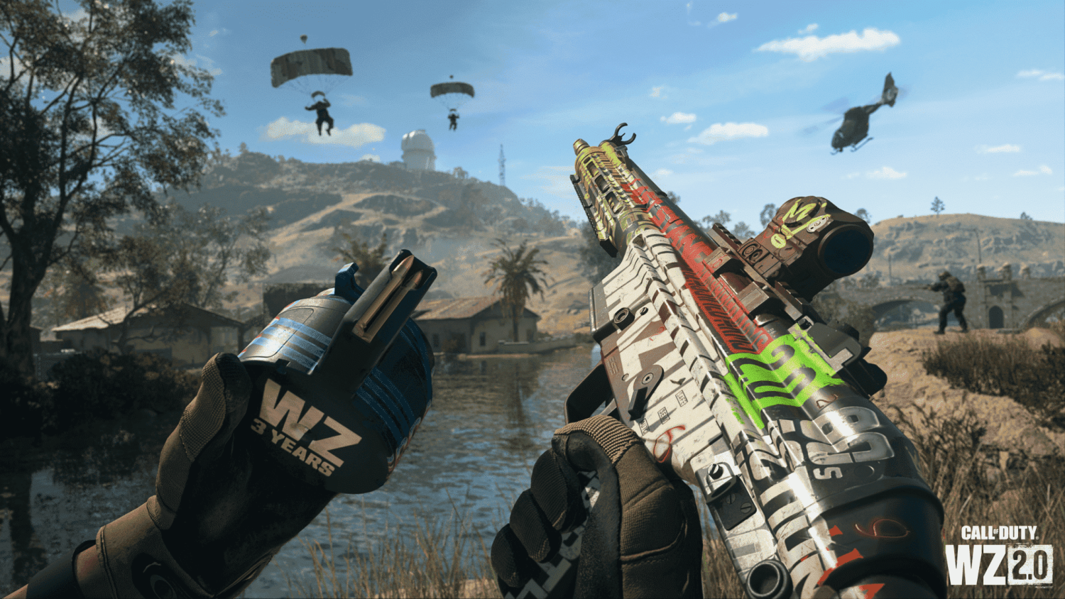 Player holding a customised colourful assault rifle and grenade labelled WZ 3 Years with parachuting soldiers and helicopter in the background