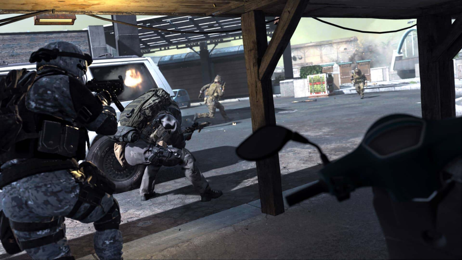Soldiers in camouflage firing weapons from under a wooden shelter near vehicles in an urban area