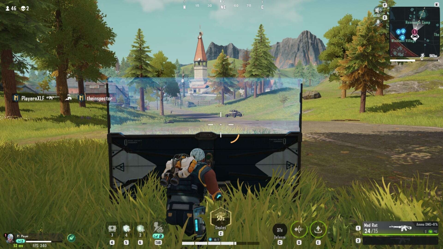 Player character crouching behind a deployable shield in a grassy open area with a village and mountains in the distance