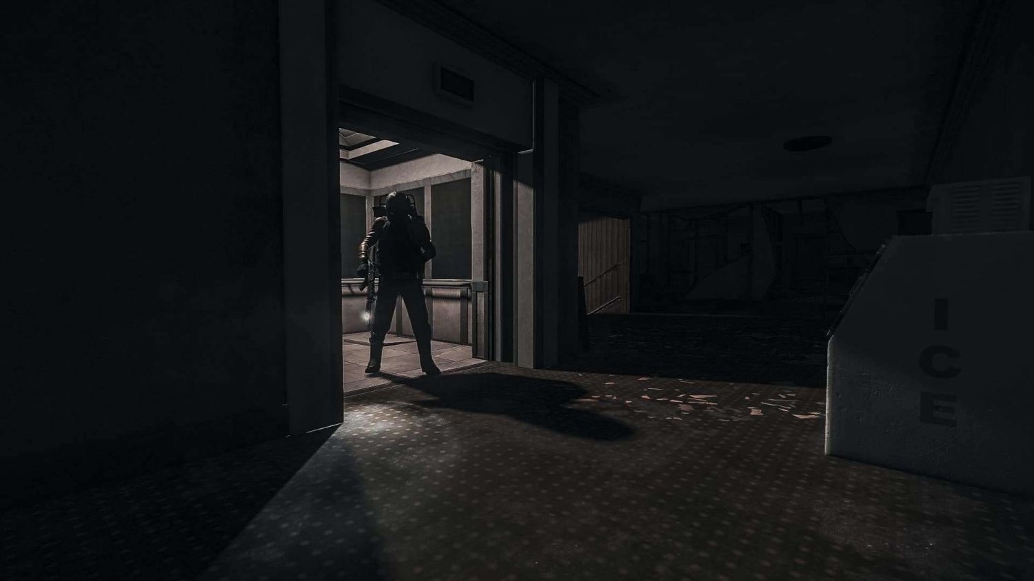 Silhouetted armed figure stands in a dimly lit corridor near an elevator with a bright shadow cast on the floor