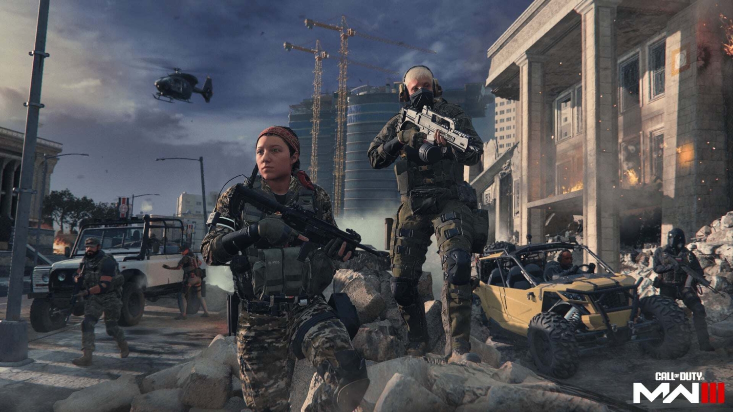 Two soldiers in tactical gear armed with assault rifles advance through rubble in a city under attack with a helicopter overhead