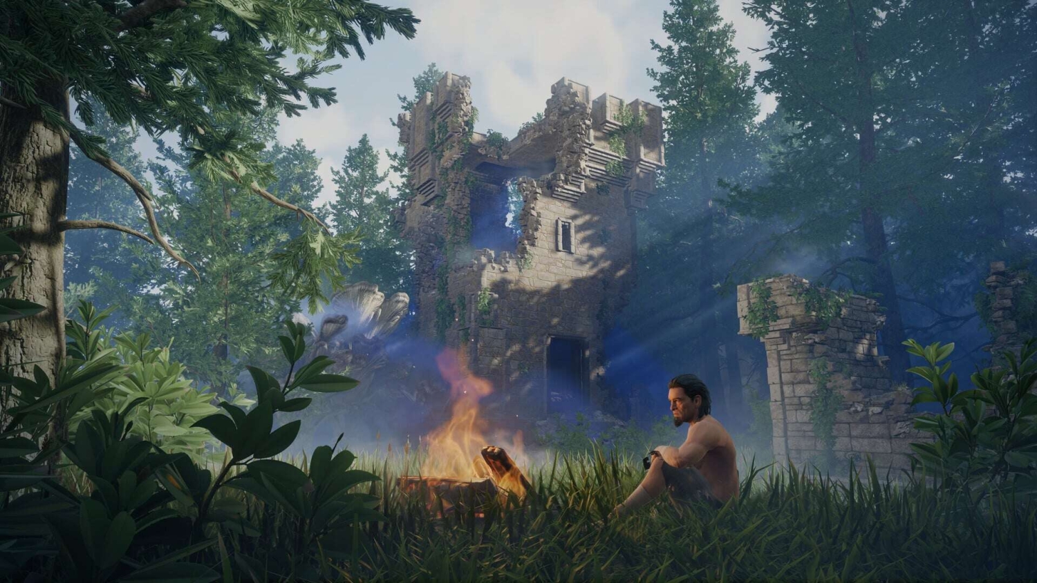 Man sitting shirtless by a bright campfire near a broken stone tower in dense forest under a clear sky