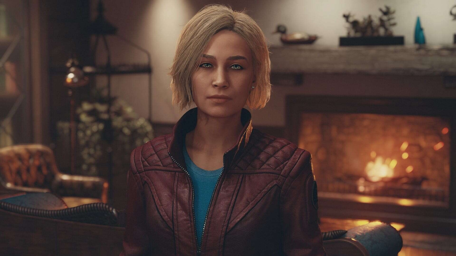 Woman with short blonde hair wearing a red jacket indoors near a lit fireplace