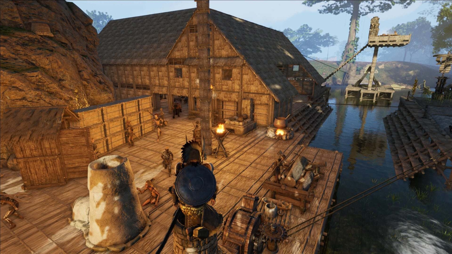 View of a medieval-style wooden settlement by the river with people and crafting stations
