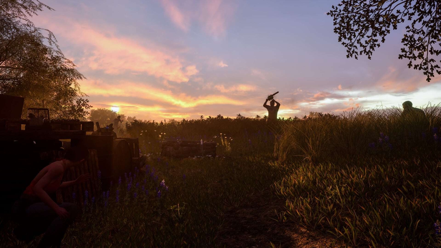 Silhouetted figure raising a chainsaw in tall grass at sunset with another person crouching nearby