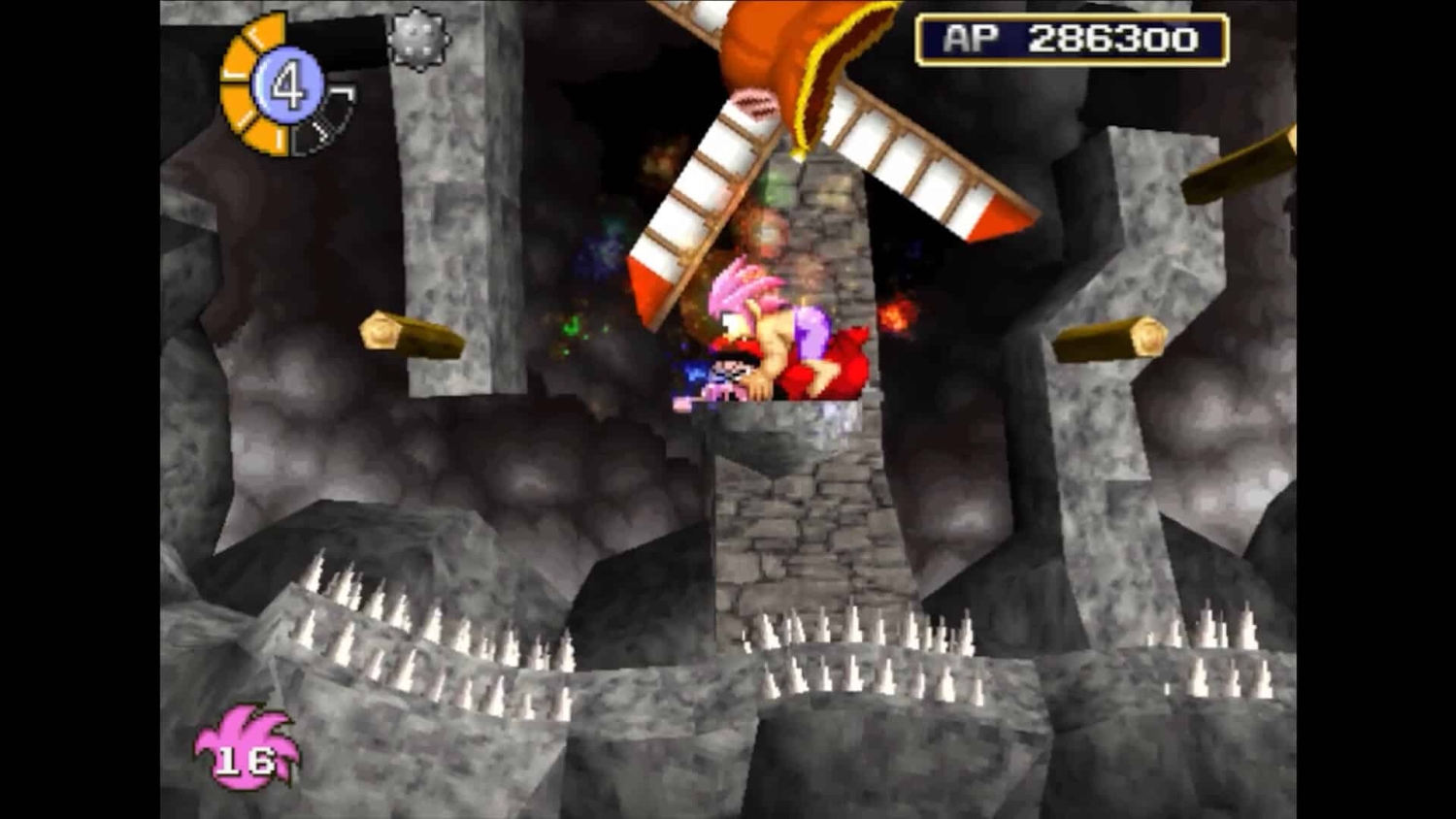 Pink-haired character crouching on a narrow stone platform with a spinning windmill above and sharp spikes below in a dark cavern