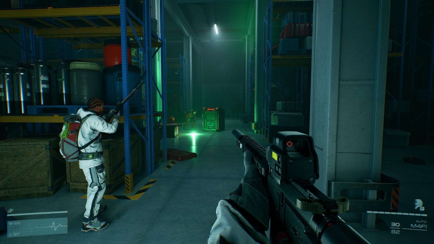 First-person shooter perspective aiming down a rifle at a warehouse aisle with teammate holding a long weapon near crates
