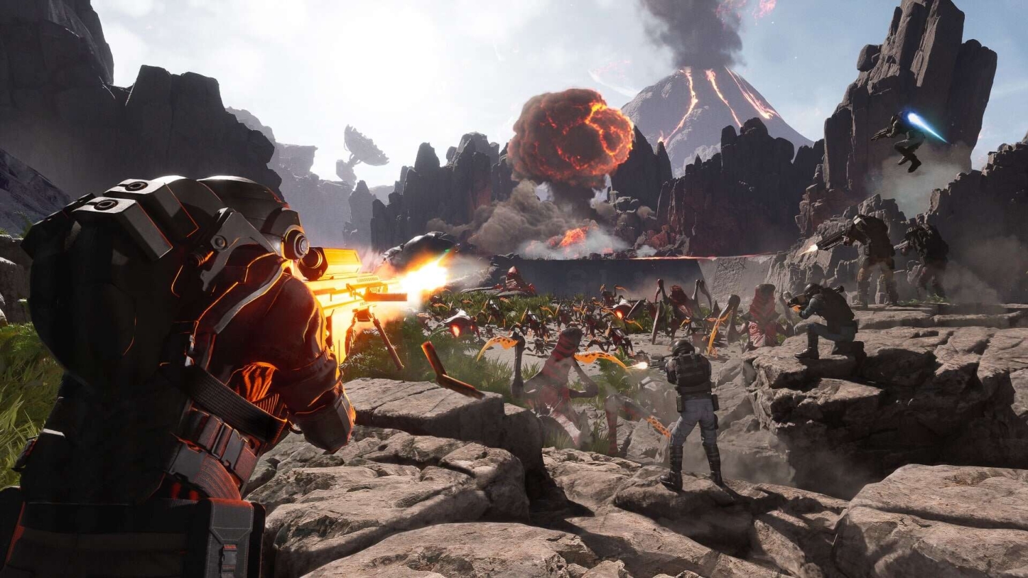 Soldiers in advanced armour firing automatic weapons at alien insect creatures on rocky volcanic terrain with erupting volcano