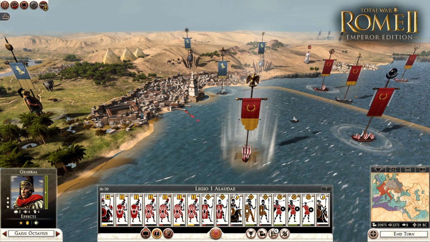 Naval units with red and blue banners engaging near a coastal city with pyramids visible inland in Total War Rome II Emperor Edition