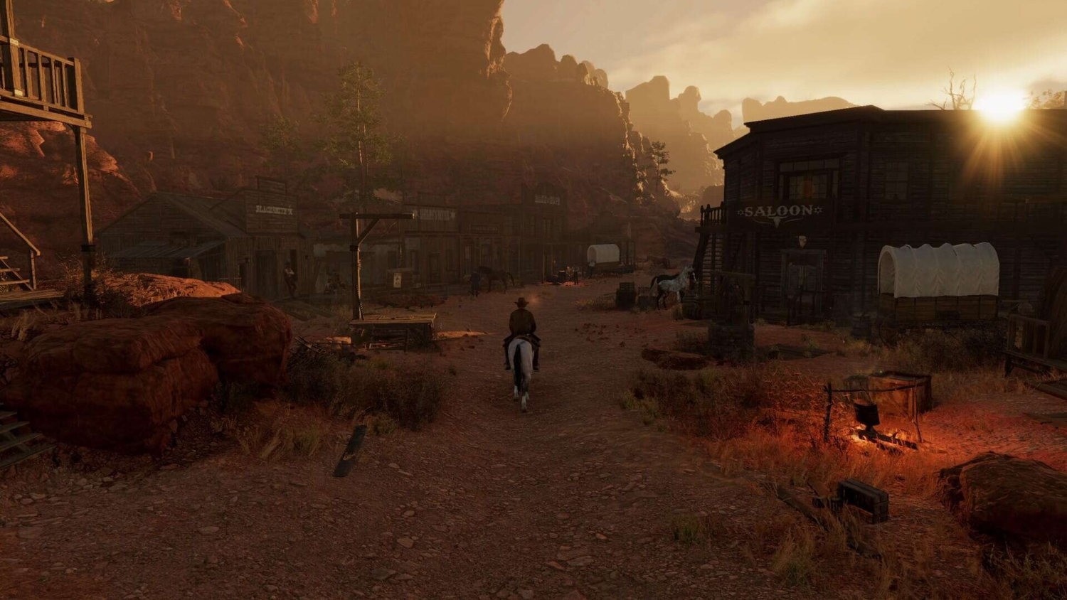 A rider on a horse travels down a dusty main street lined with wooden buildings and a saloon at sunset