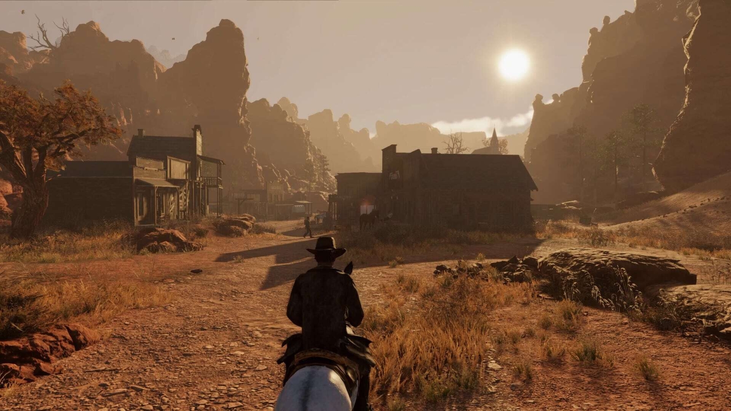 Person on horseback rides toward a rustic western town at sunset surrounded by rocky terrain