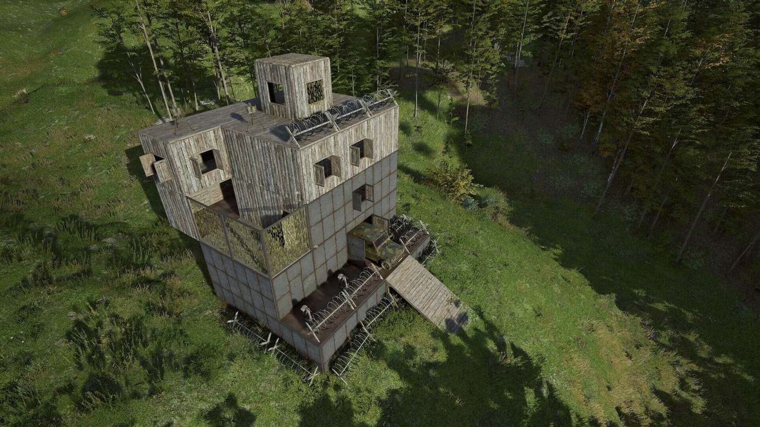 Wooden and metal watchtower with barbed wire surrounded by forest and grassland