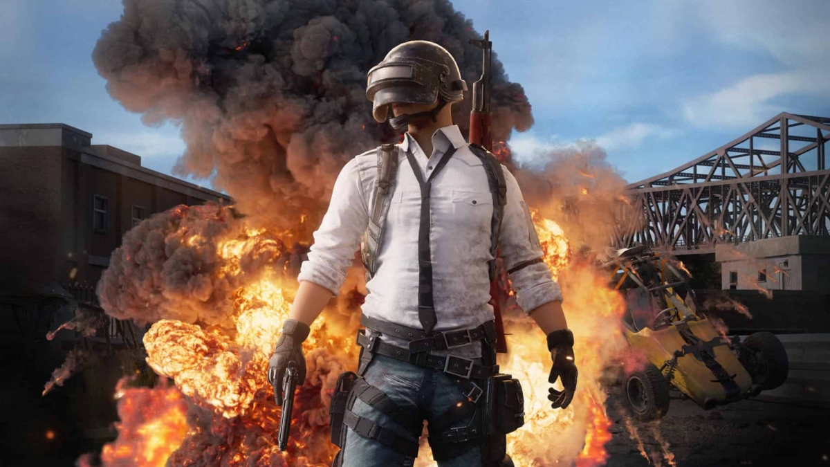 Player character in helmet and white shirt walking away from a large explosion with a burning vehicle behind